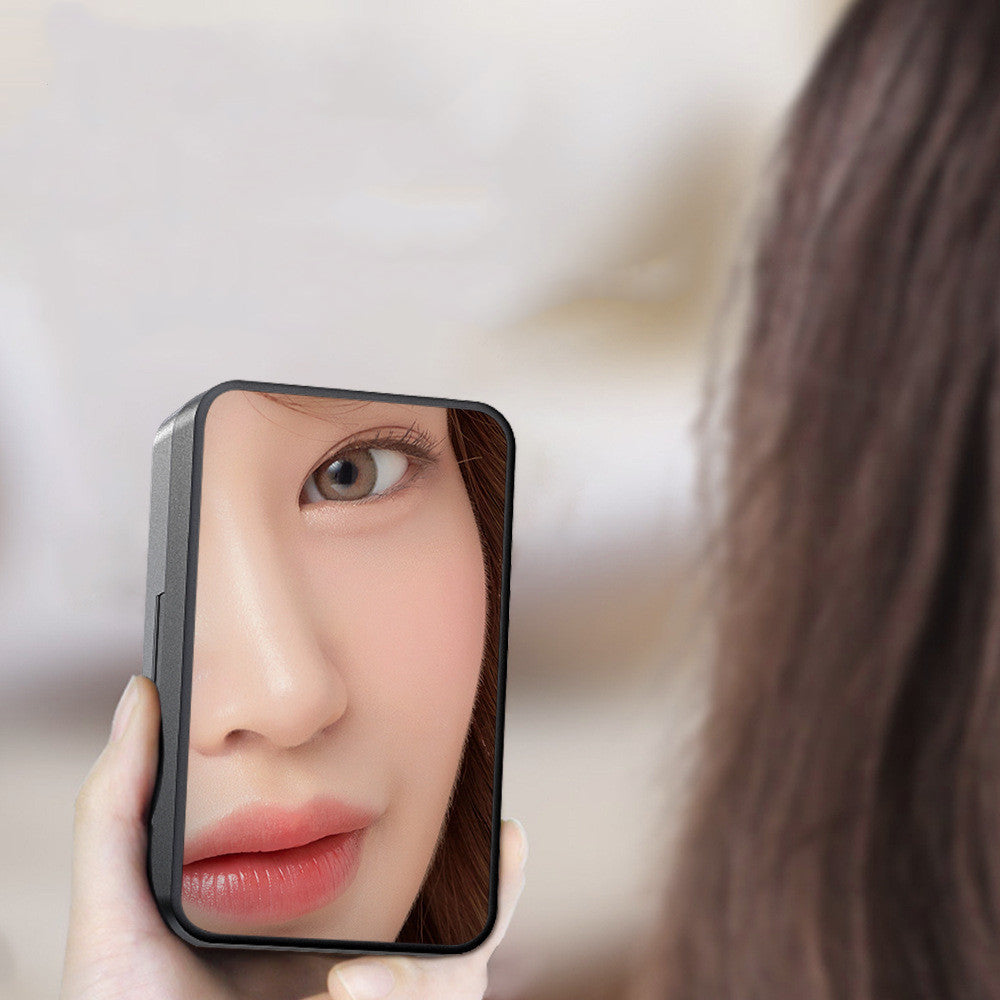 Close-up of a person holding a compact mirror revealing a soft-focus view of their face.
